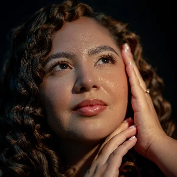 Dra. María Fernanda Olarte con las manos junto al rostro, piel sana e hidratada